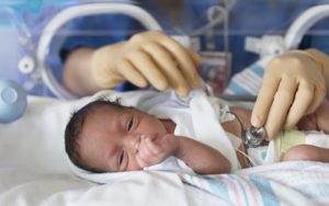 Female doctor examining newborn baby in incubator