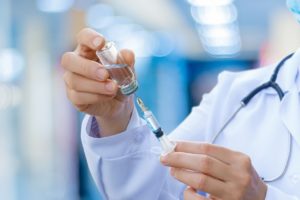 The doctor prepares the syringe for vaccination.