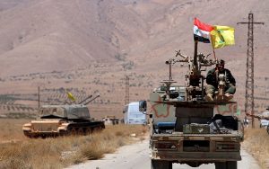 Hezbollah and Syrian flags flutter on a military vehicle in Western Qalamoun