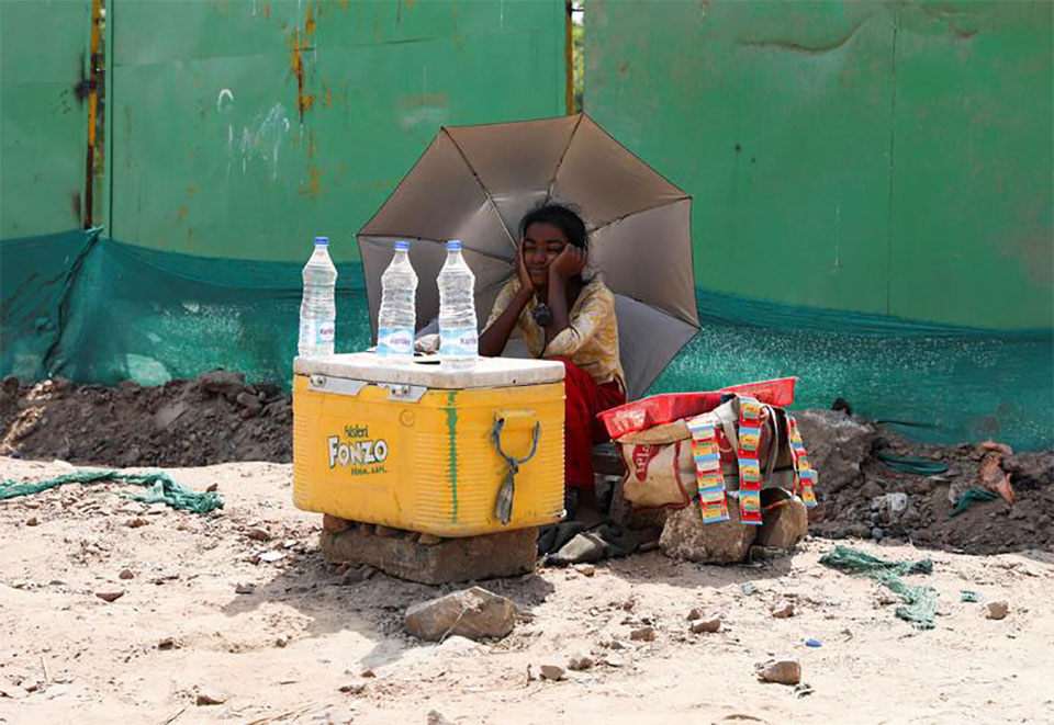 دختر هندی که با استفاده از چتر از خود در برابر نور خورشید مراقبت میکند