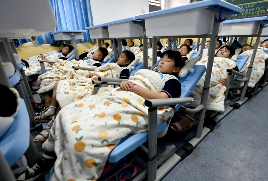 چرت اجباری ظهرگاهی دانش آموزان روی نیمکت های جدید تاشو در مدرسه ای در شهر هاندان چین