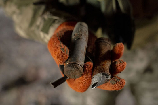 یک سرباز اوکراینی مهمات منفجر نشده روسی در یک ساختمان ویران شده در شهر خارکیف به دست گرفته است