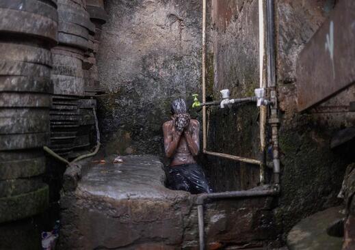 حمام صبحگاهی یک نوجوان با آب سرد در هوای سرد زمستانی در بخش قدیمی شهر دهلی هند