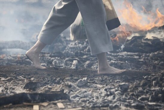 راهب بودایی در حال پاشیدن نمک روی هیزم سوزان برای عبور از روی آن