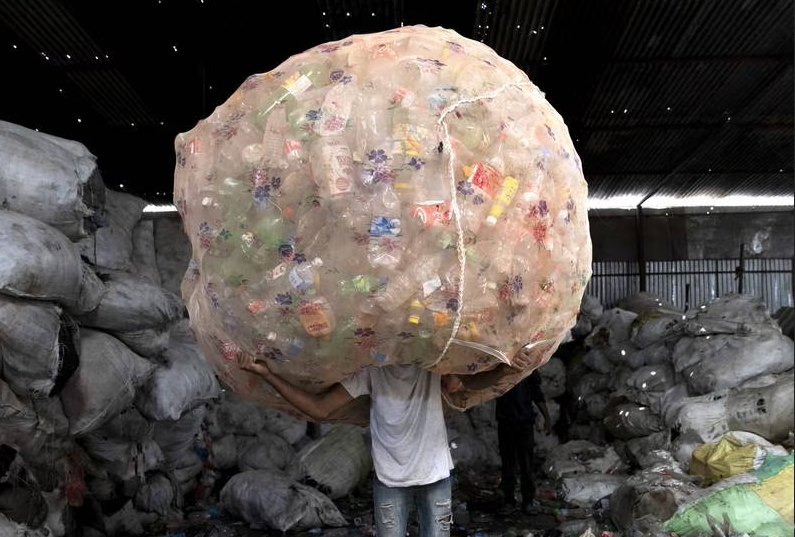 حمل بسته بطری های پلاستیکی در مرکز مجموعه زباله توسط کارگر"Kathmandu" نپال