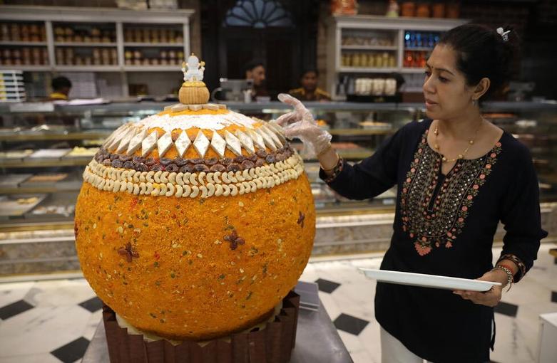 یک زن در حال تزئین یک "لادو" غول پیکر 500 کیلوگرمی