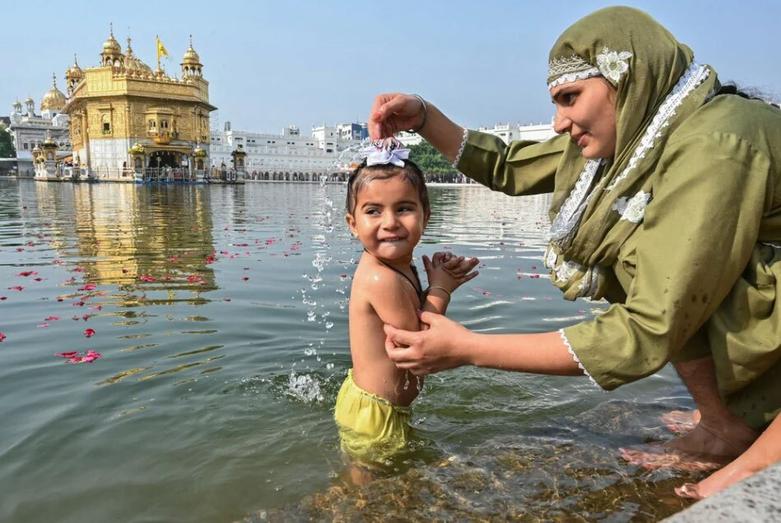 شستشوی یک کودک سیک هندی در دریاچه معبد طلایی