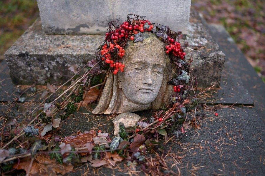 سر یک مجسمه آسیب‌دیده، روی سنگ قبری در گورستان