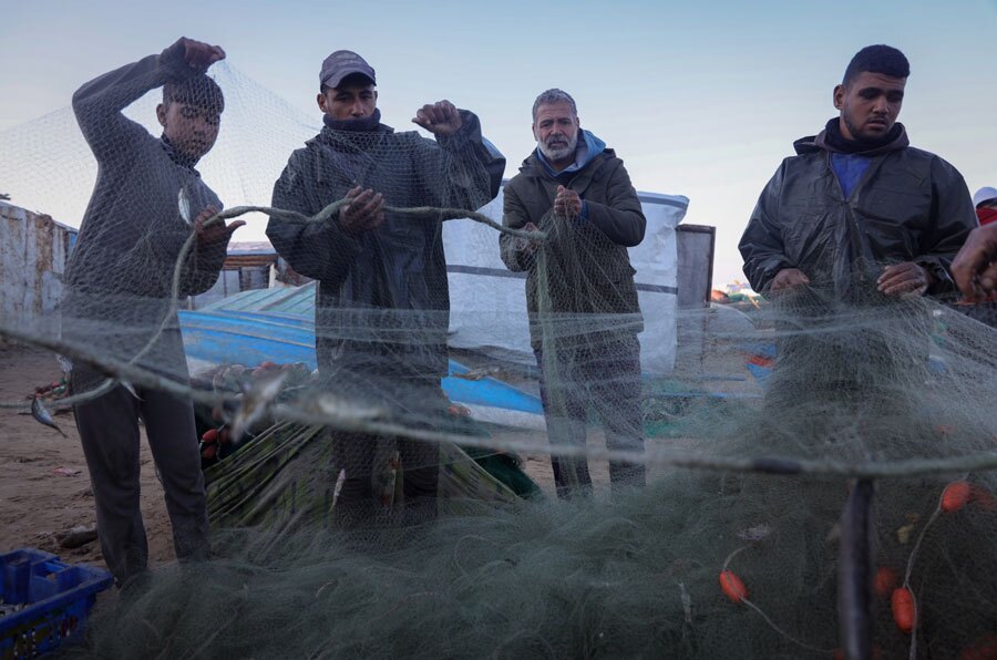 ماهیگیران در حال باز کردن تور در ساحل نوار غزه
