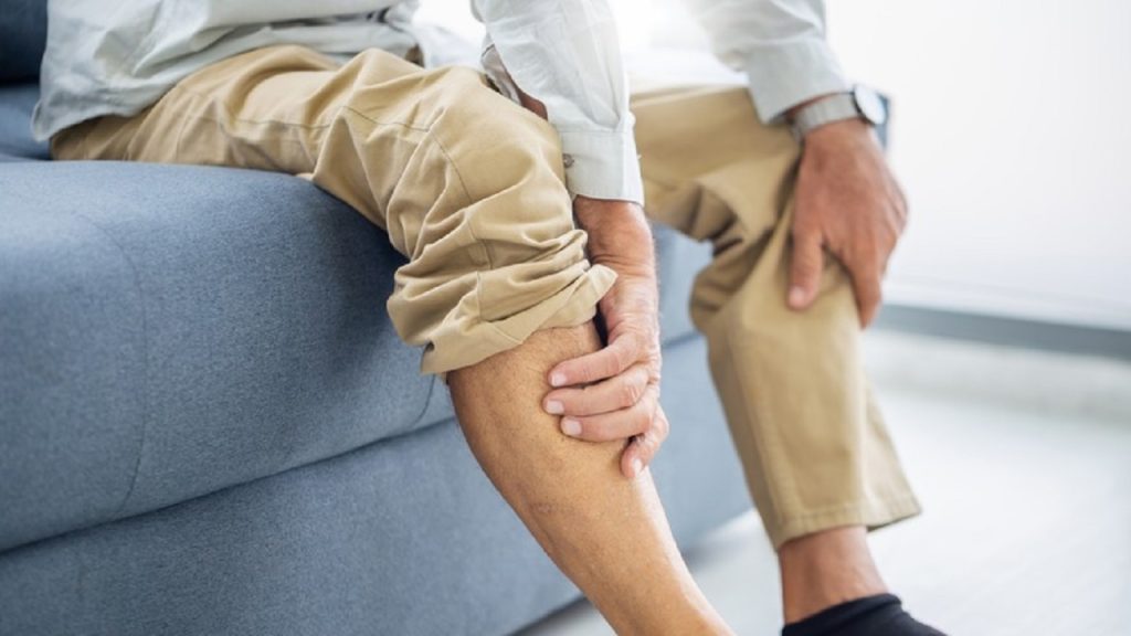 Old,Man,Suffering,From,Knee,Pain,Sitting,Sofa,In,The